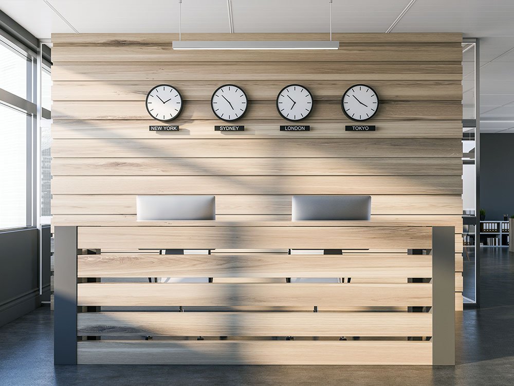 Empfangsbereich aus Holz – Objektbau und Innenausbau von der Tischlerei Siebert Moderner Empfangstresen aus hellem Holz mit integrierten Uhren – Beispiel für individuellen Objektbau