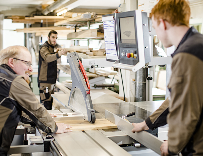 Tischlerteam bei der Holzbearbeitung an einer modernen Kreissäge in der Werkstatt Siebert Mehrere Tischler arbeiten gemeinsam an einer Formatkreissäge – präzise Holzbearbeitung in der Werkstatt