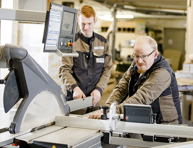 Erfahrene Tischler bei der Holzbearbeitung in der Werkstatt der Tischlerei Siebert in Melle Zwei Tischler arbeiten konzentriert an einer Kreissäge – präzise Holzverarbeitung in der Werkstatt